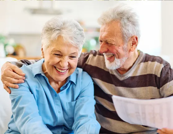 An adult couple laughing whilst sitting on the sofa