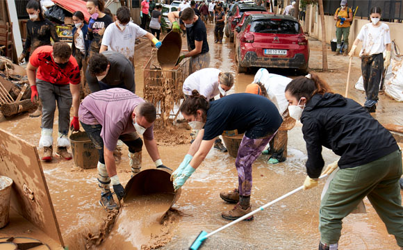 gente con marcarillas sacando barro de la calle