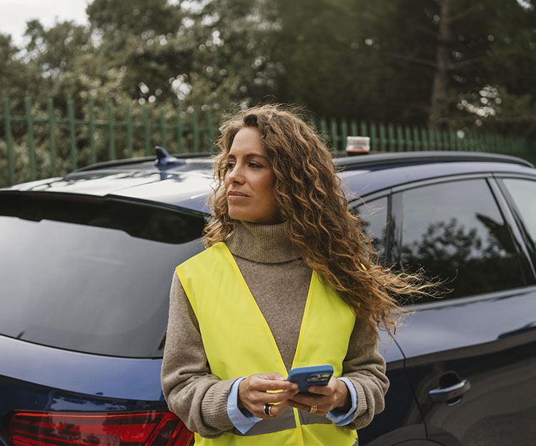 chica apoyada en un coche con el móvil en la mano