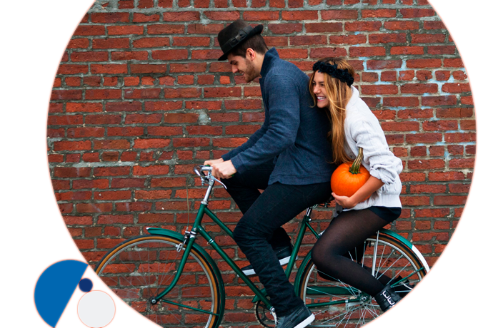 pareja divertida en bicicleta llevando una calabaza