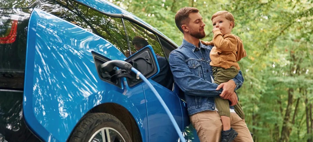 Padre e hijo junto a un coche eléctrico cargando