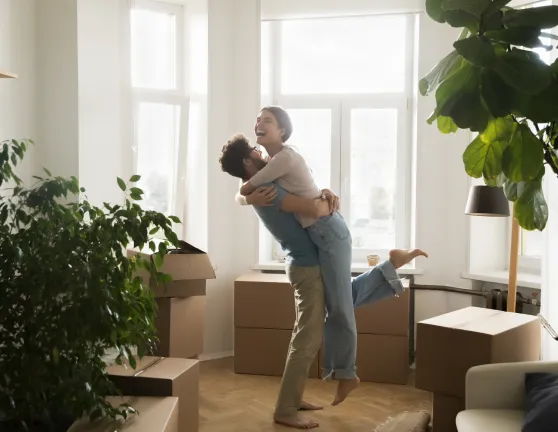 Pareja abrazándose y sonriendo en casa con mudanza