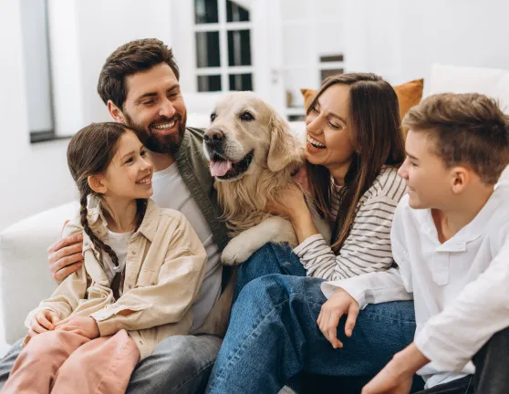 Familia feliz junto con un perro en el sofá de su casa