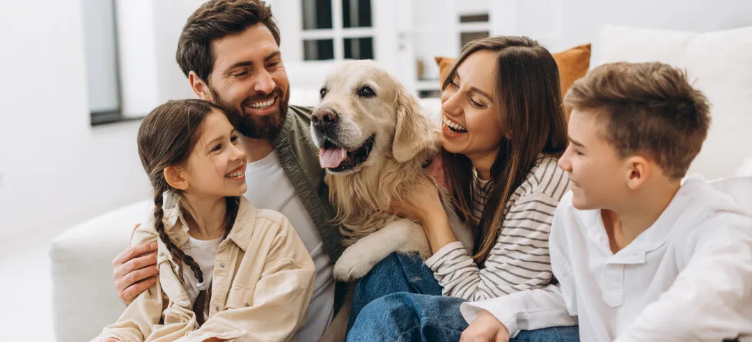 Familia feliz junto con un perro en el sofá de su casa