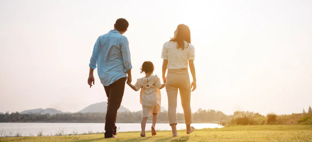 Familia agarrada de la mano caminando descalza por un campo de césped