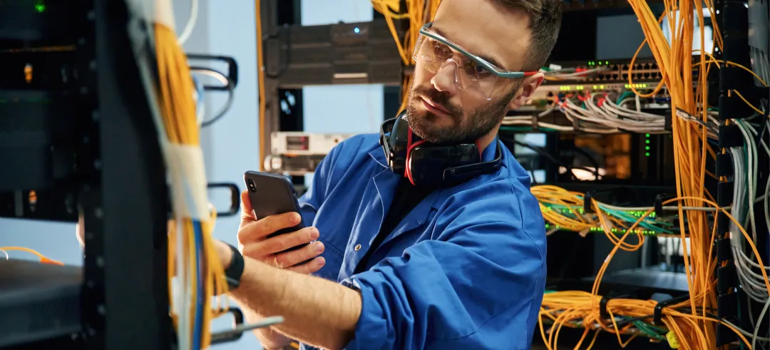 Técnico trabajando en la gestión de cables de servidores en un centro de datos.