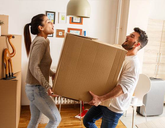 Pareja cargando una caja de cartón durante una mudanza